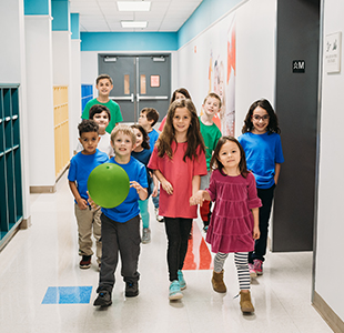 Group of happy students walking together in the school hallway